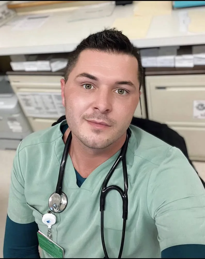 Cody, psych LPN, in scrubs at the nurses' station