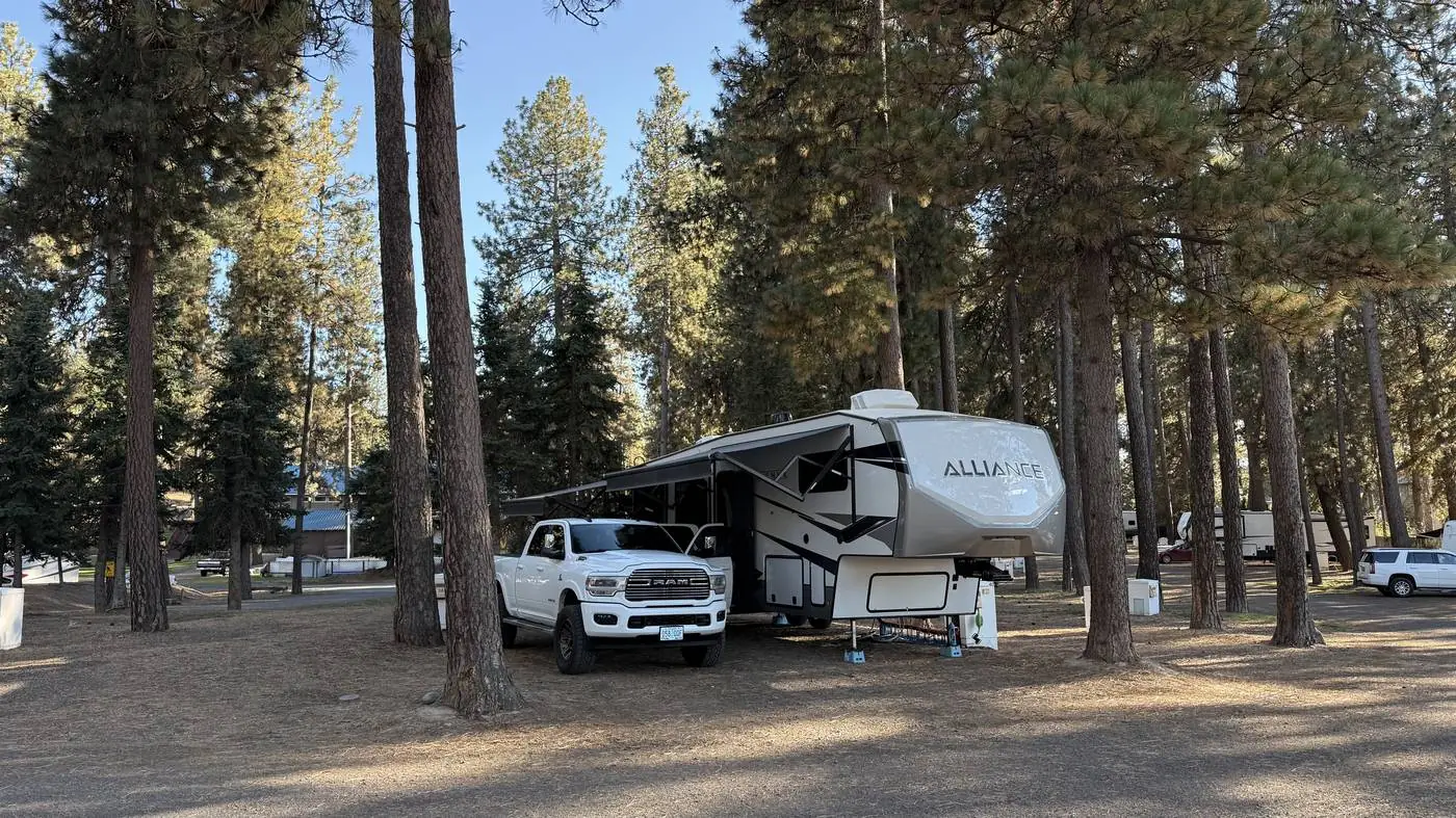 The Alliance fifth wheel and Ram parked among tall pines